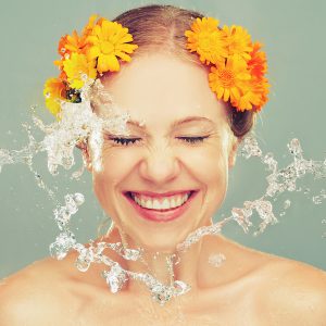 beauty laughing girl with splashes of water and yellow flowers